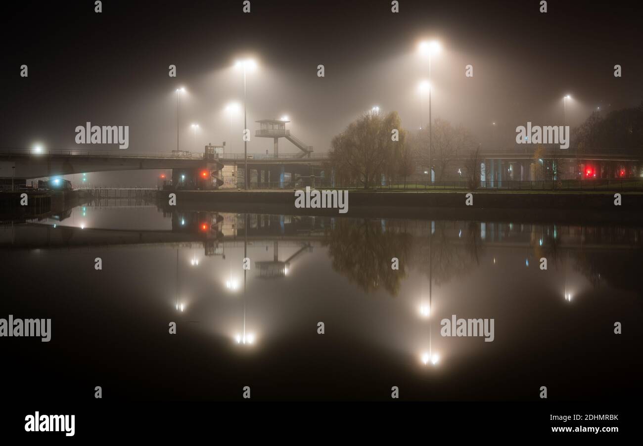 Streetlights are diffused by mist rising from Cumberland Basin on an autumn night on Bristol's Floating Harbour. Stock Photo