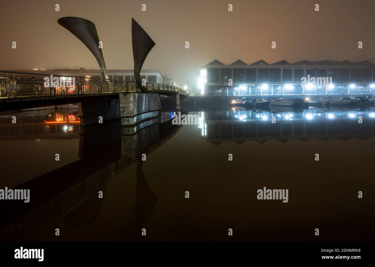 Old warehouses now converted into bars are shrouded in mist beside Pero's Bridge on an autumn night on Bristol's Harbourside Stock Photo