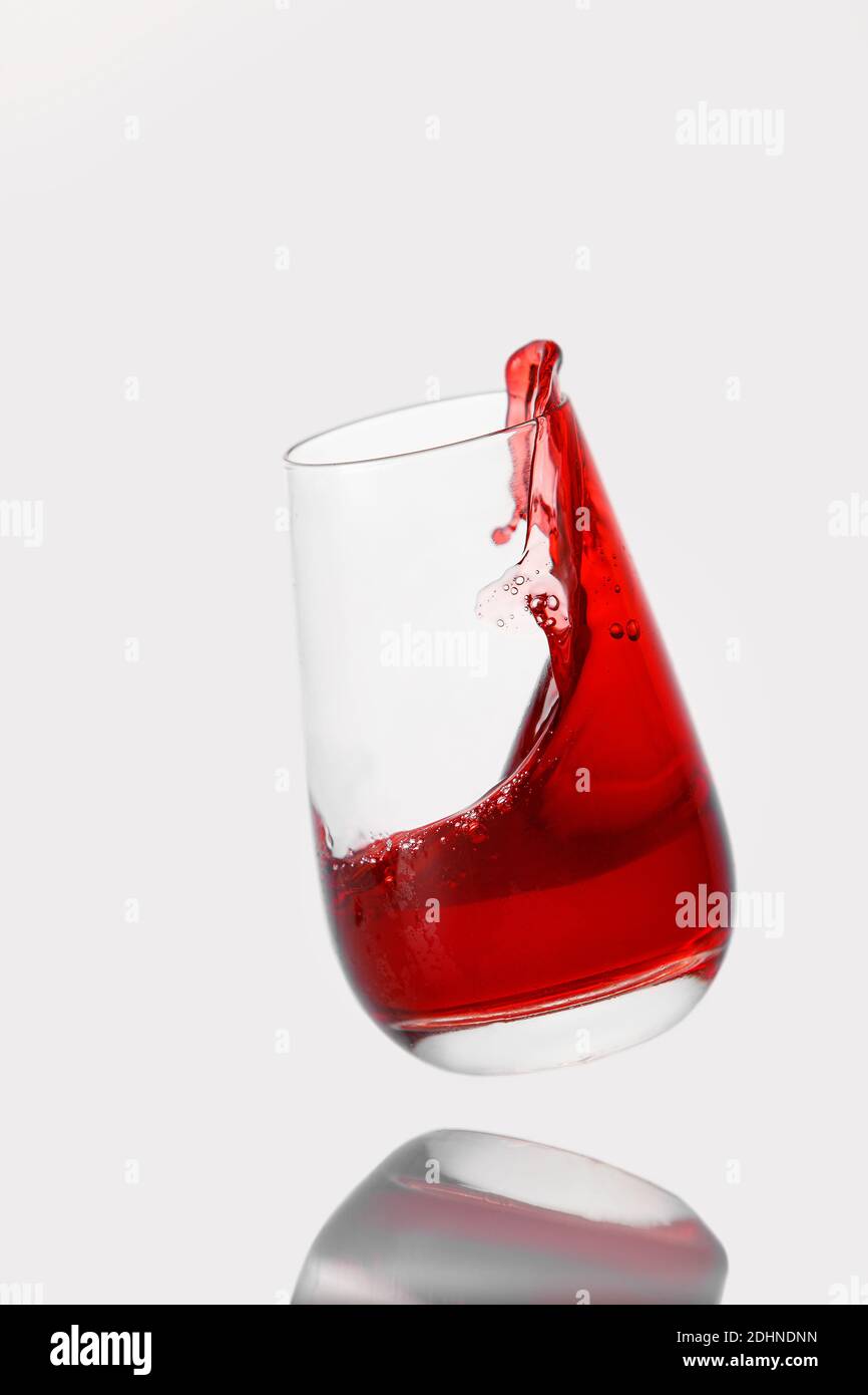 Red cocktail splashes in a glass on a white background Stock Photo
