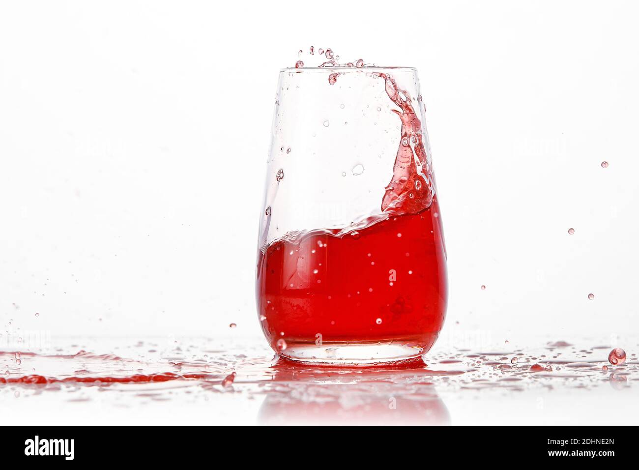 Red cocktail splashes in a glass on a white background Stock Photo