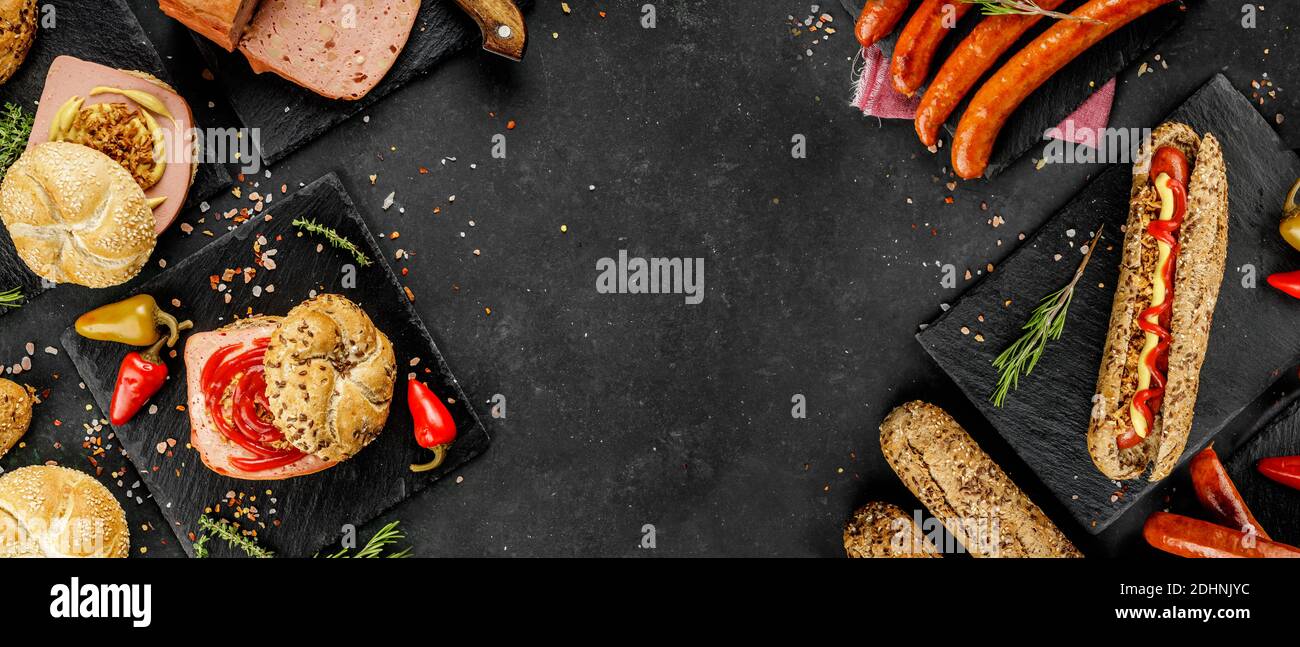 Flat lay composition of delicious hot dogs and sandwiches with different toppings on the dark background Stock Photo