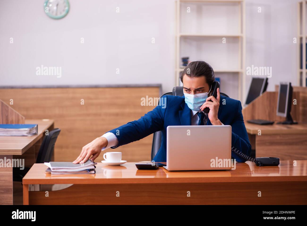 Young employee working in the office wearing mask Stock Photo - Alamy