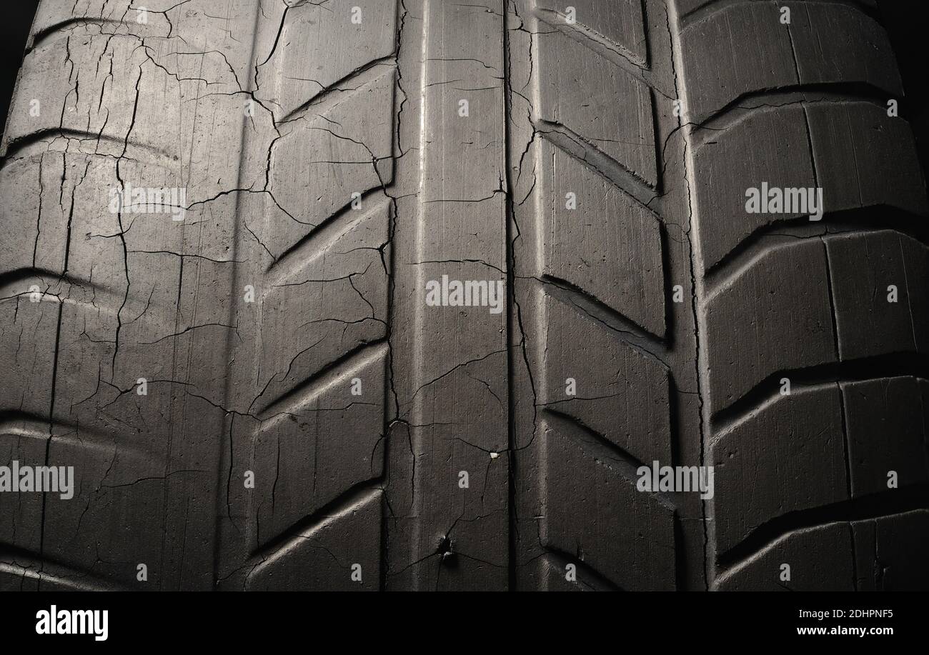 Old black tire with worn tread and cracks, worn old car tire tread, old