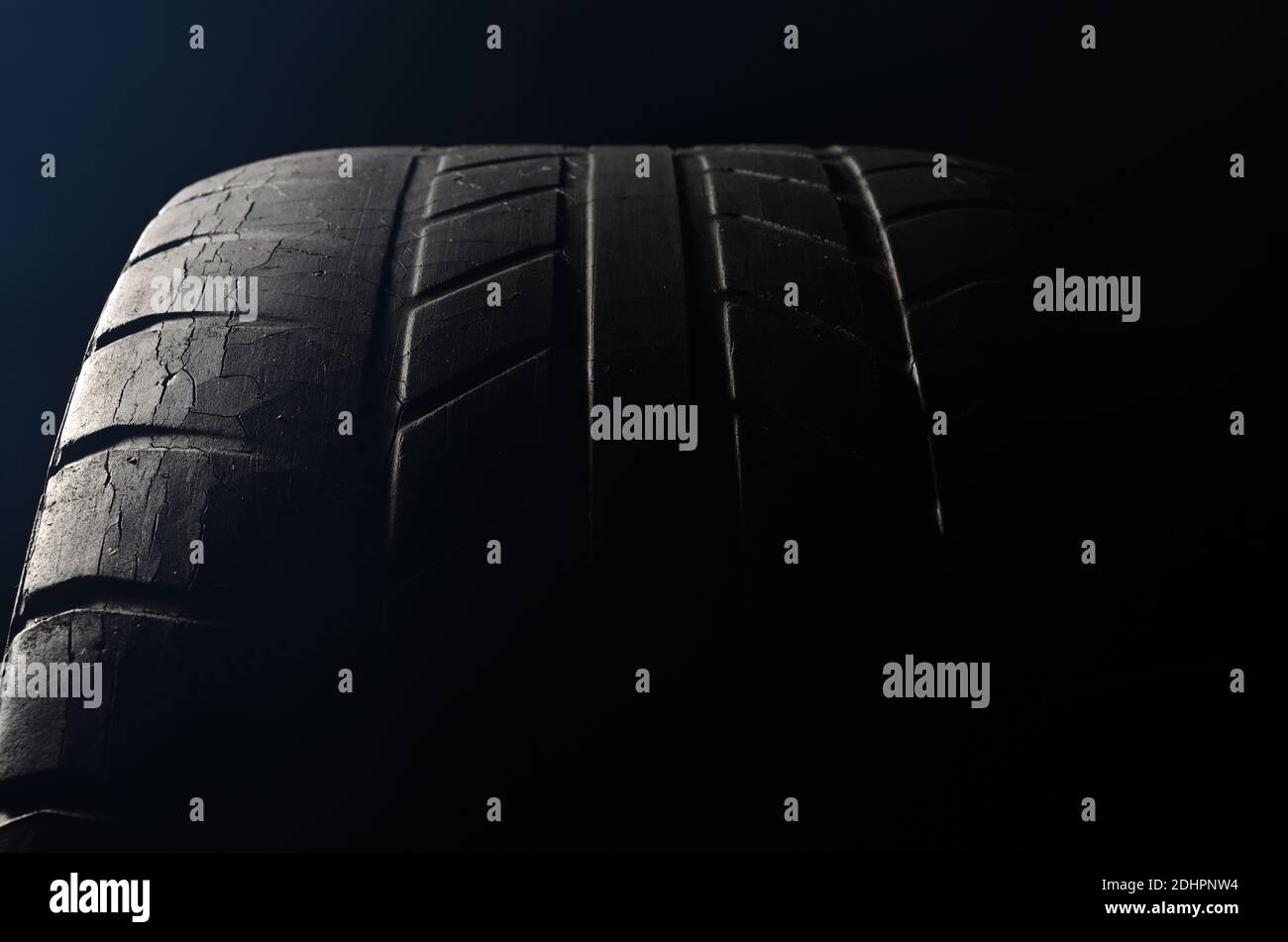 Old black tire with worn tread and cracks, worn old car tire tread, old