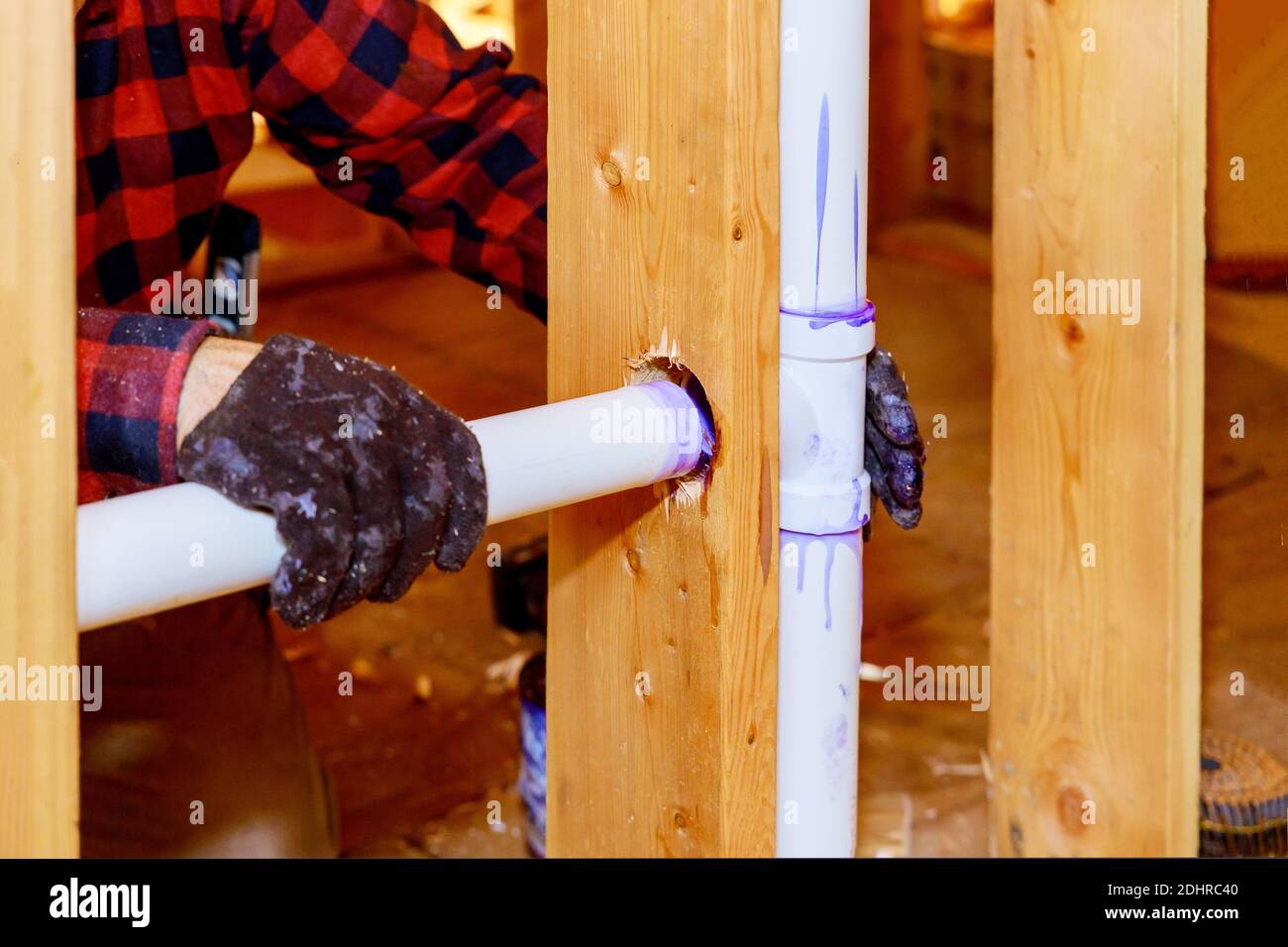 A plumber in a plastic sewer pipe into putting glue on a pvc pipe Stock
