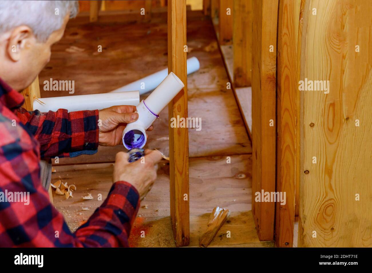 Plumber jointing glue PVC sewage drain pipes on a house under