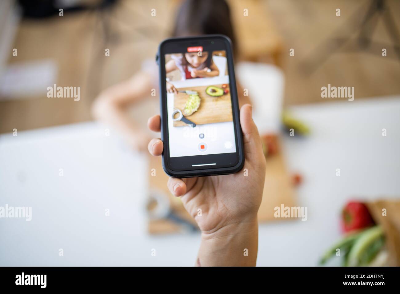Female hand with a smartphone recording a little girl cutting an ...