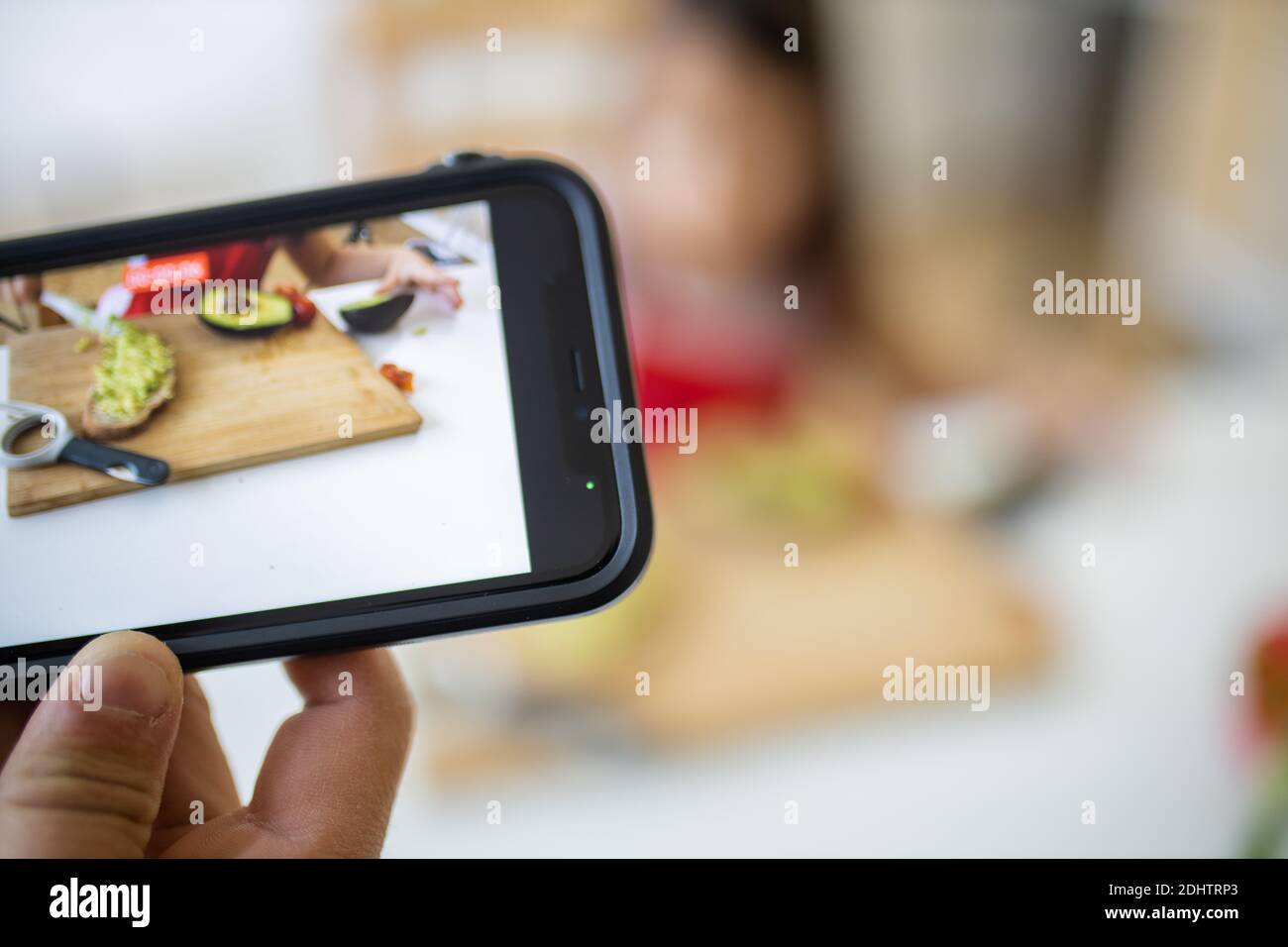 Hand with a smartphone recording a little girl cutting an avocado Stock ...
