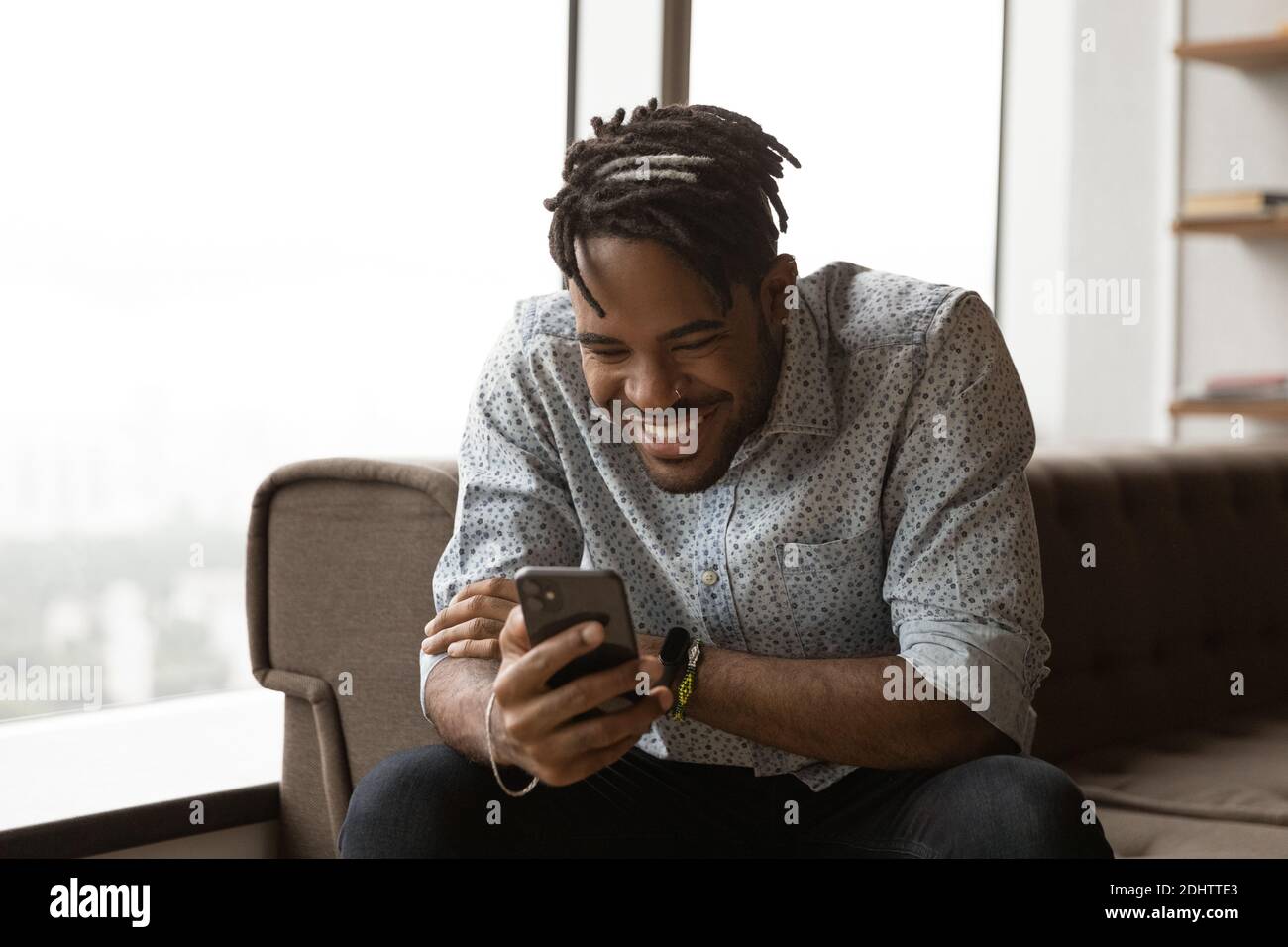 Smiling biracial man have fun using smartphone Stock Photo
