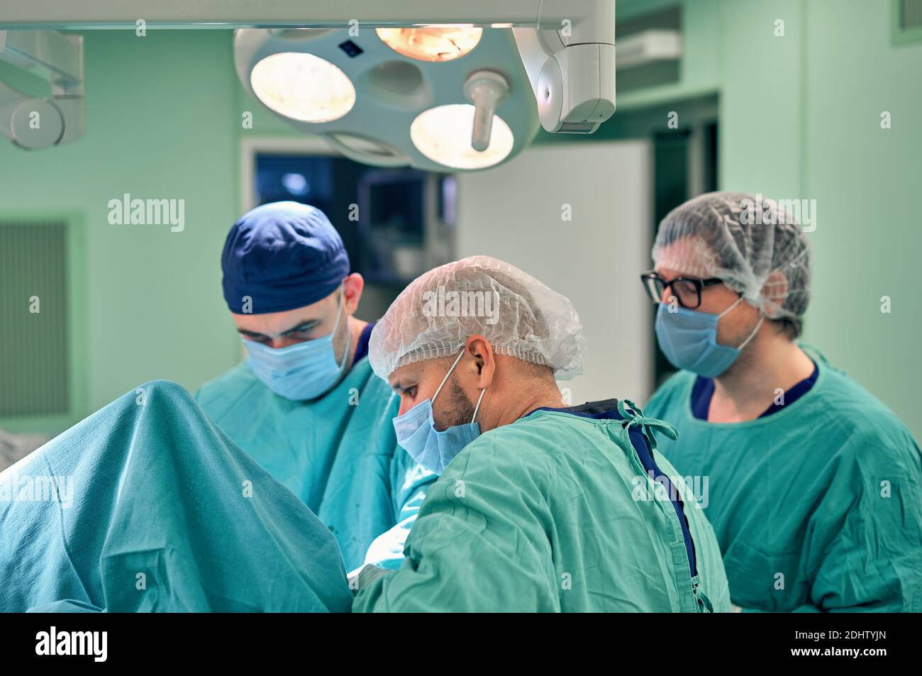 Physicians in Surgery looking down at patient Stock Photo - Alamy