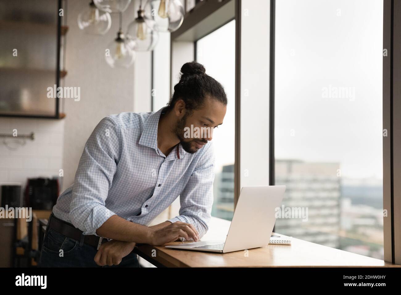 Serious biracial man work on computer at workplace Stock Photo