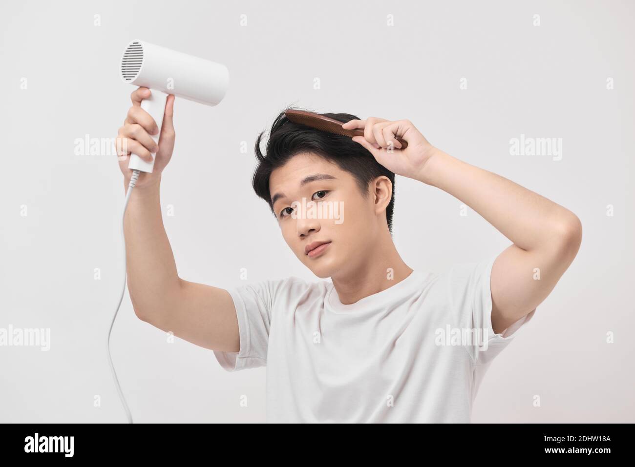 Asian fun young man 20s years old in white shirt hold blow dry hair isolated on white background, Stock Photo