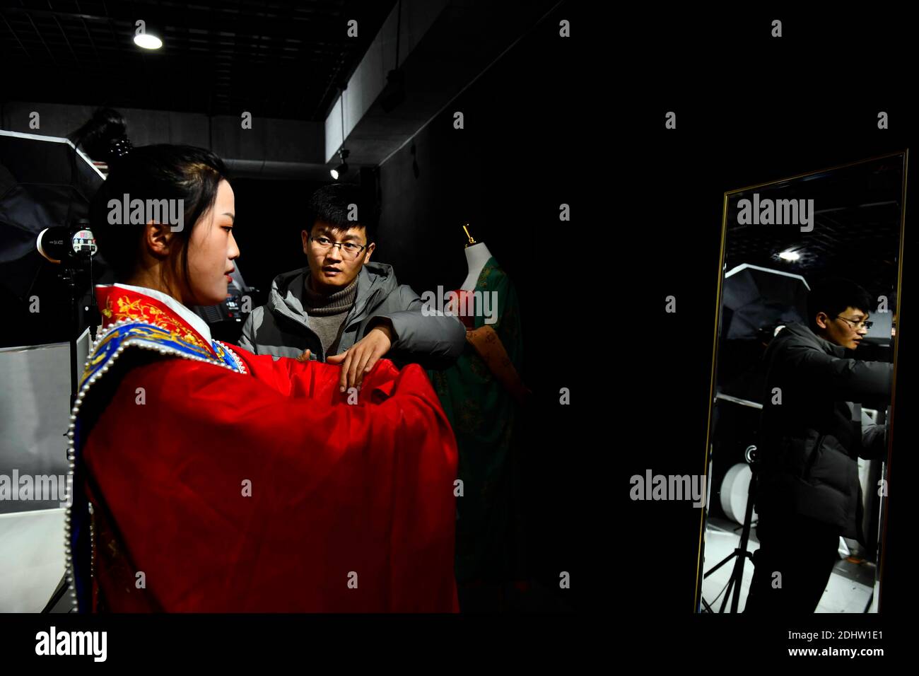 (201212) -- JINAN, Dec. 12, 2020 (Xinhua) -- Hu Chunqing (R) guides a student to perform a ritualistic salute at a secondary vocational school in Caoxian County, east China's Shandong Province, Dec. 11, 2020. While continuing with his study, Hu Chunqing, who is now a PhD student, returned to his hometown in Daji Township of Caoxian County, east China's Shandong Province in 2018 to help his wife Meng Xiaoxia start their own business in making and selling performance costumes and hanfu, a type of traditional clothing of the Han ethnic group. Their business kept booming with Meng working as the d Stock Photo
