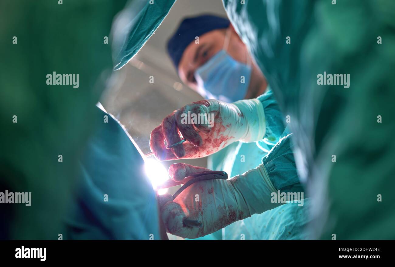 Physicians in Surgery looking down at patient Stock Photo - Alamy