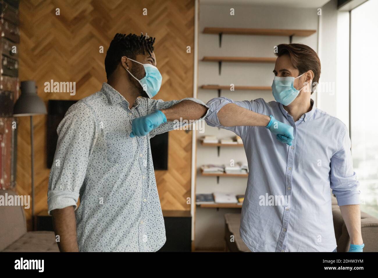 Diverse men touch elbows greeting during coronavirus pandemics Stock Photo