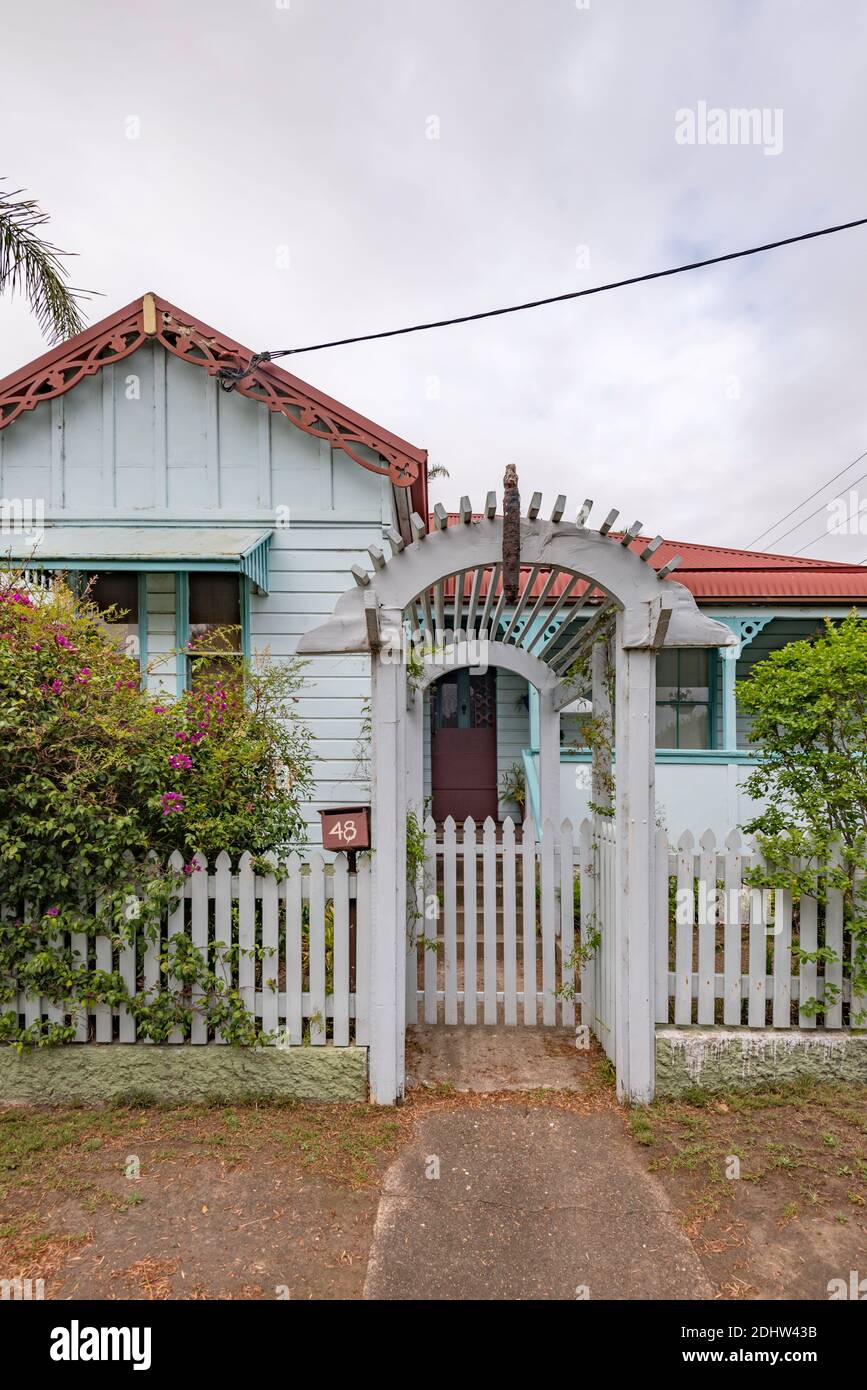 A simple weatherboard Federation cottage with a timber fretwork gable and an archway over a gated path in a picket fence in country Australia Stock Photo