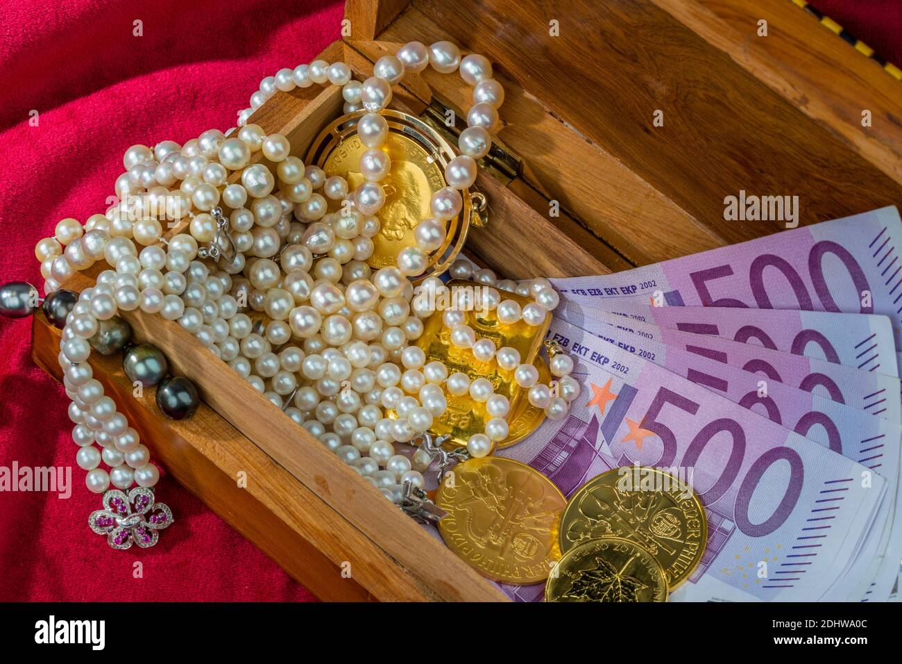 Gold in Münzen und Barren mit Schmuck auf rotem Samt. Symbolfoto für Reichtum, Luxus, Reichensteuer, 500 Euro Scheine, Stock Photo