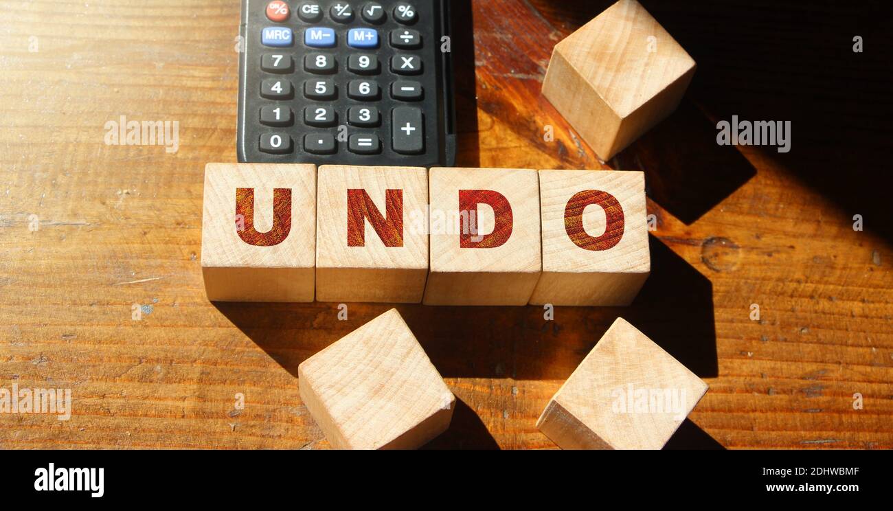 Undo word on wooden cubes with letters, and calculator. Lifestyle and state of mind concept. Stock Photo