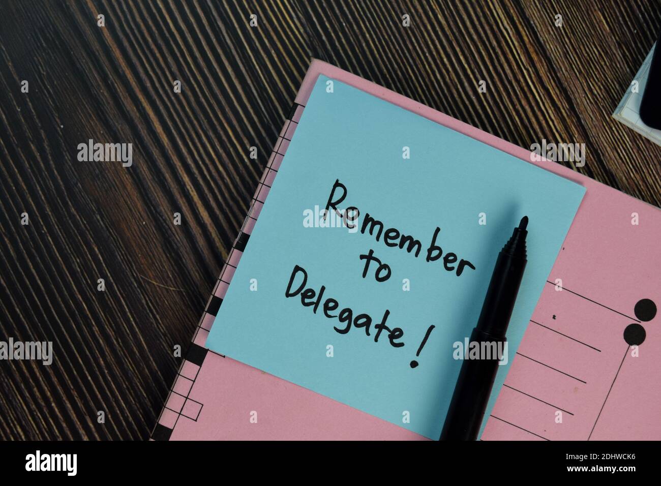 Remember to Delegate! write on sticky notes isolated on Wooden Table. Stock Photo