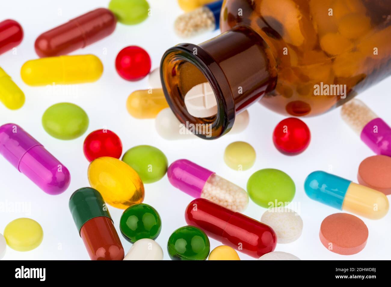 Viele Tabletten mit einem Glasbehaelter. Symbolfoto fuer Sucht und Kosten in der Medizin und bei Medikamenten. Stock Photo