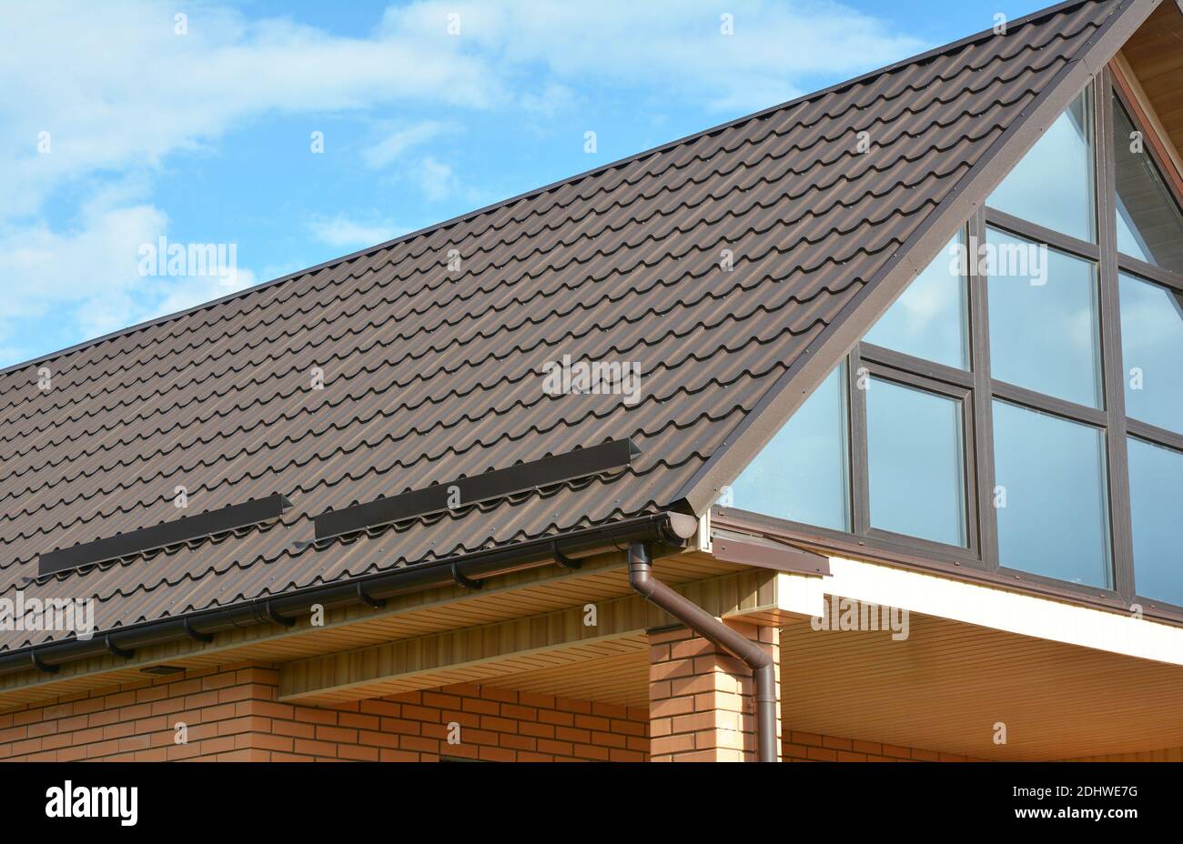 Building Modern House Construction with metal roof, rain gutter system and roof protection from snow board, snow bar, snow guards. Stock Photo
