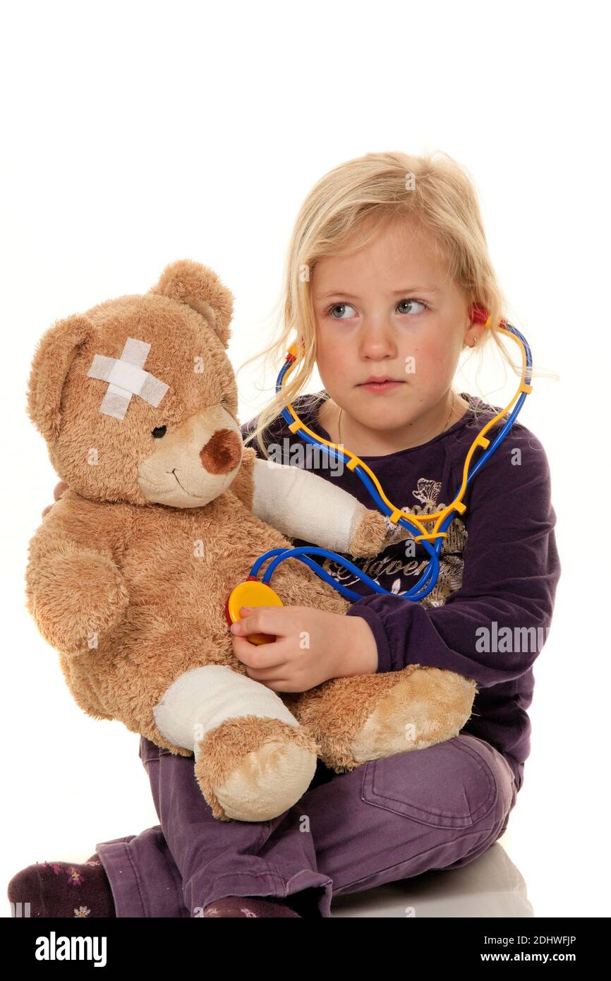 Kind mit Stethoskop als Arzt. Kinderarzt untersucht Teddybär Stock Photo