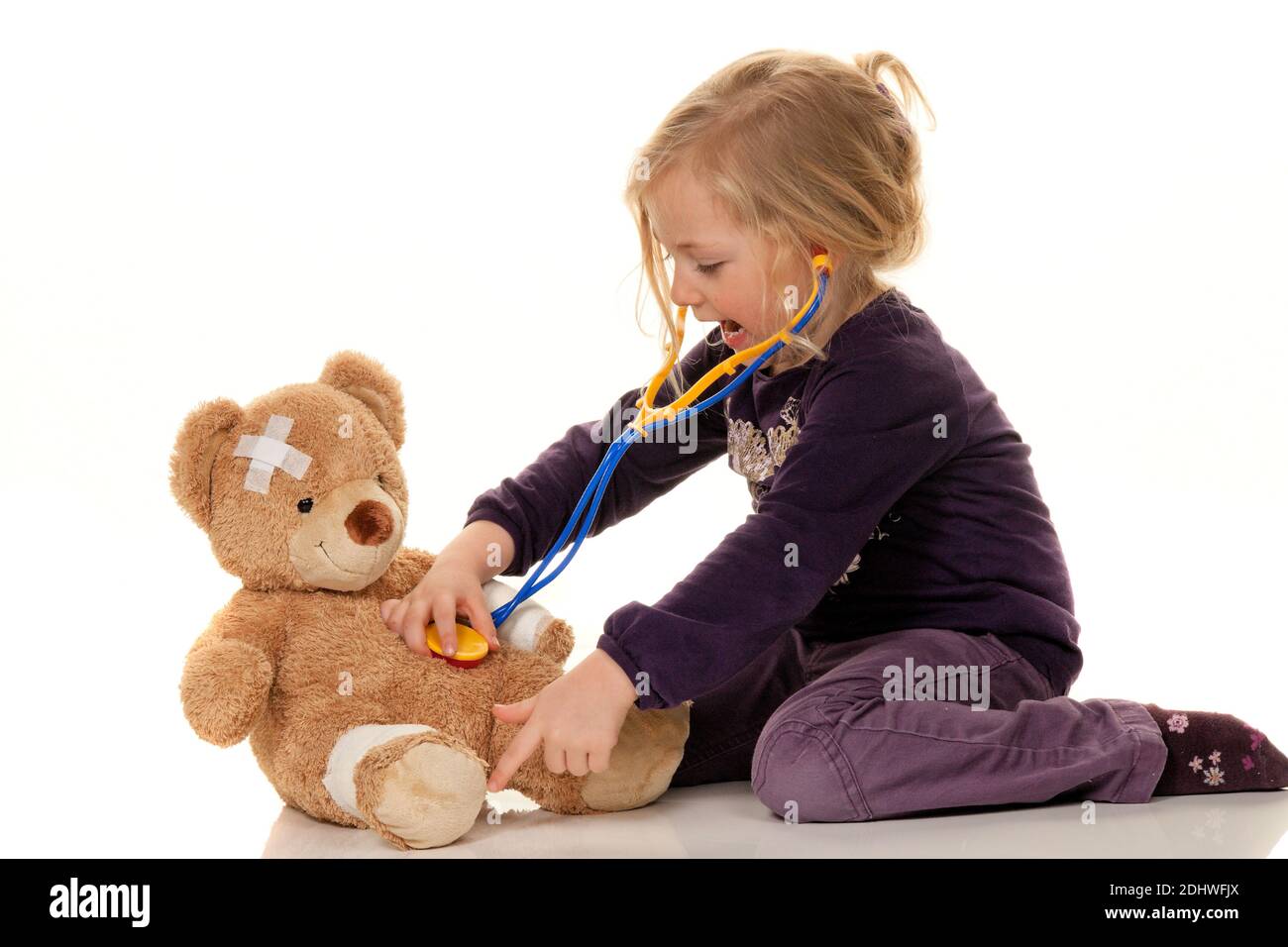 Kind mit Stethoskop als Arzt. Kinderarzt untersucht Teddybär Stock Photo
