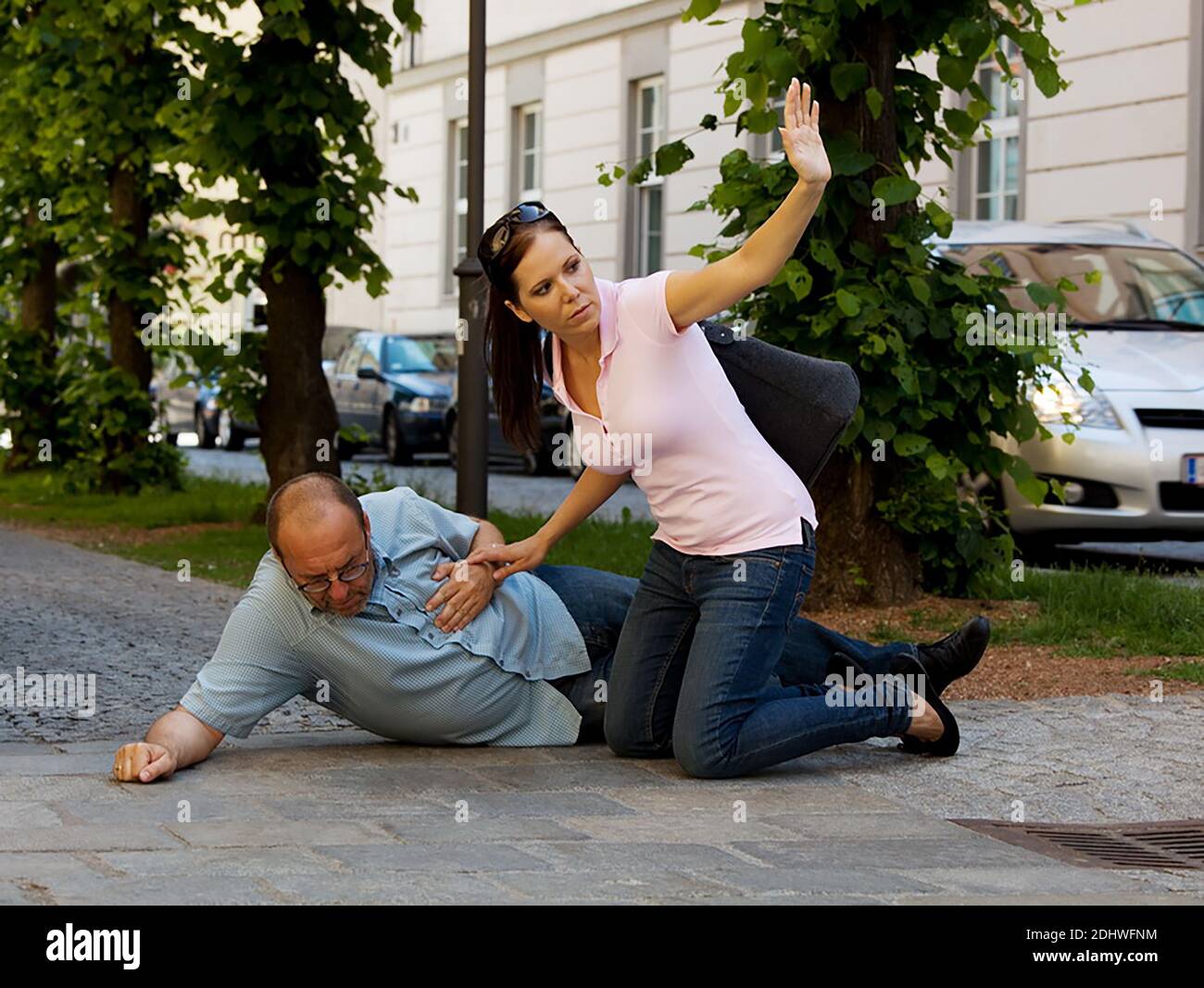 Ein Mann hat einen Schwindelanfall oder einen Herzanfall. Eine Frau kommt zu Hilfe. Stock Photo