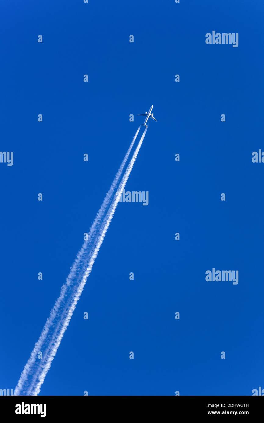 Ein Flugzeug mit Kondensstreifen am blauen Himmel. Sehnsucht für die nächste Urlaubsreise Stock Photo