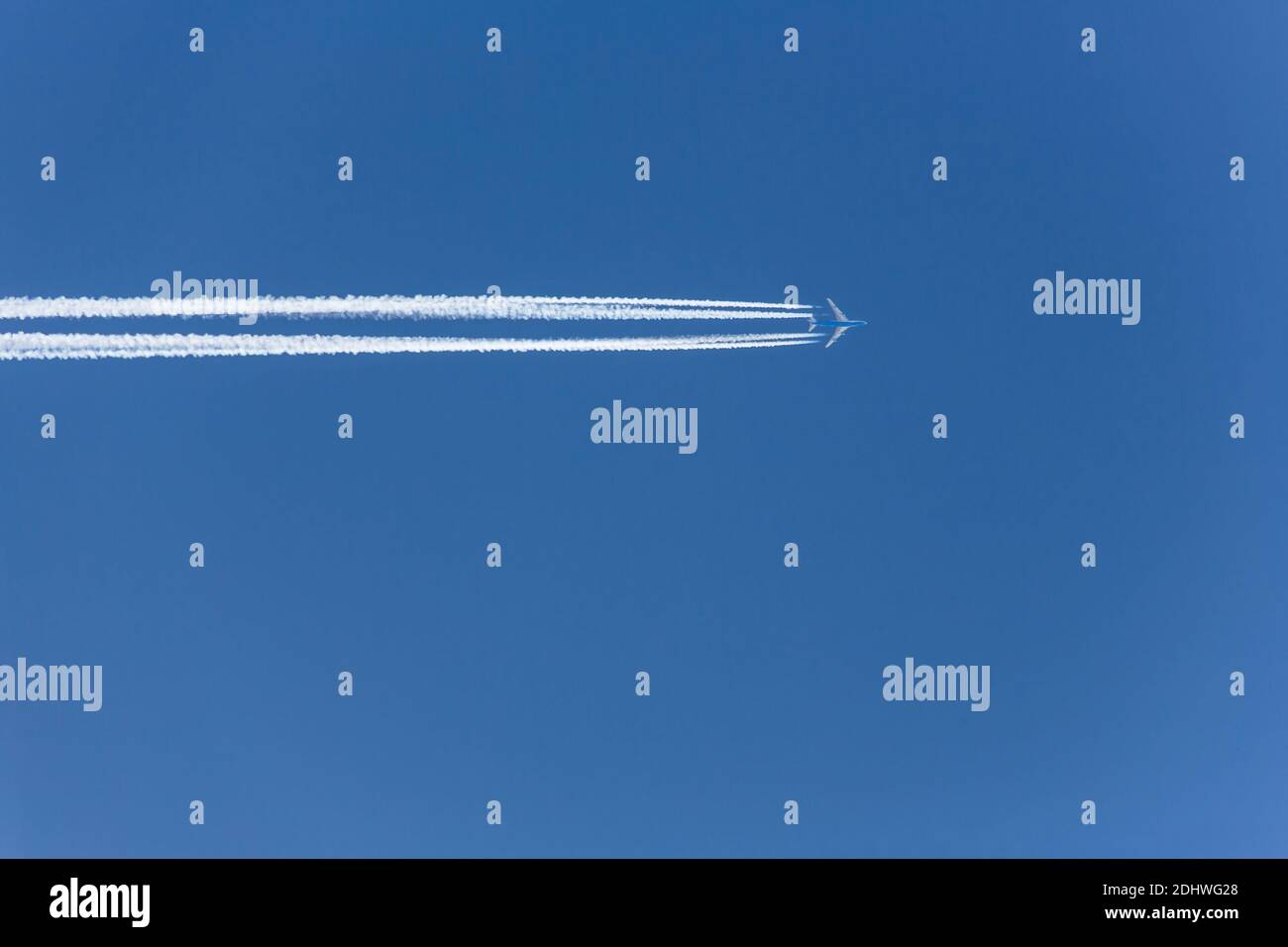 Ein Flugzeug mit Kondensstreifen am blauen Himmel. Sehnsucht für die nächste Urlaubsreise Stock Photo
