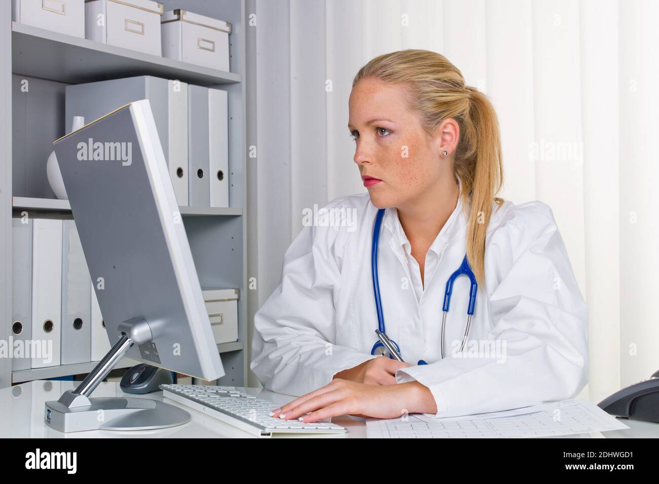 Eine junge Ärztin mit Stethoskop in ihrer Arztpraxis. Stock Photo