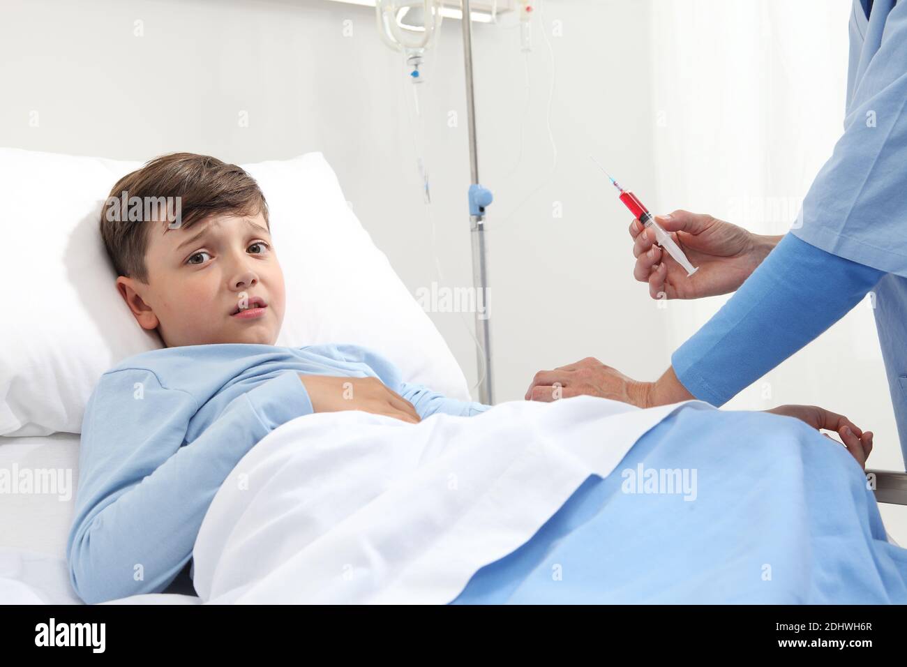 Afraid child lying in bed in hospital room looking at camera scared by