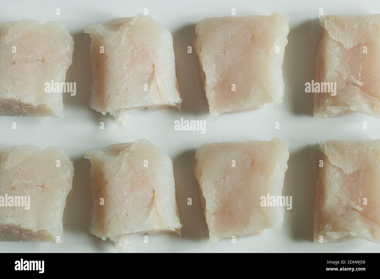 Pieces of raw hake in line on white ceramic texture background Stock ...