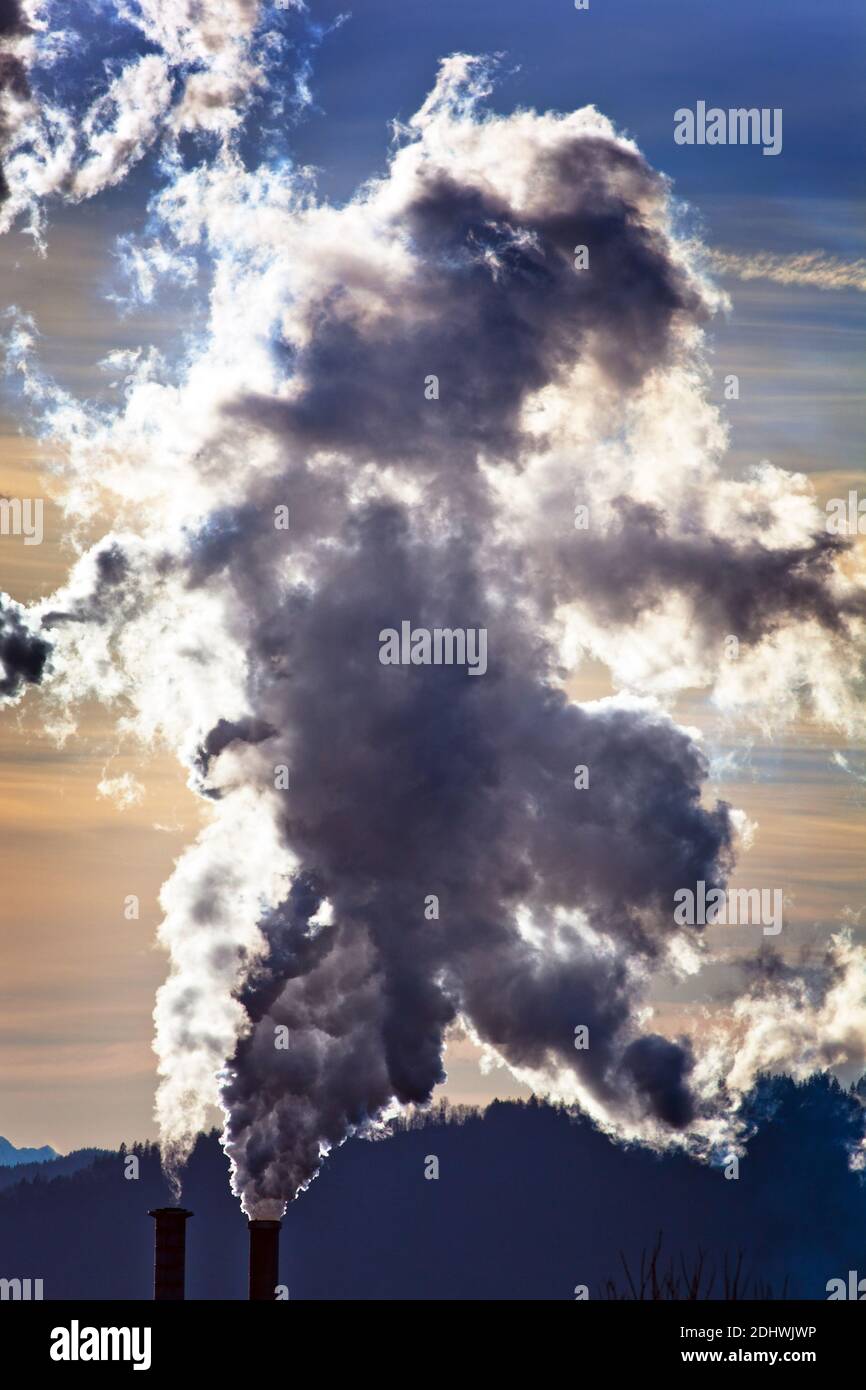 Die rauchenden Schlote einer Fabrik vor blauem Himmel. Aus Schornsteinen steigt Rauch auf Stock Photo