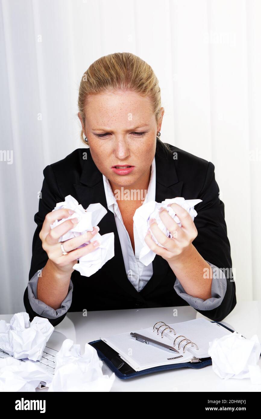 Eine Frau im Büro mit Papierknäuel. Ärger, Stress und Frust am Arbeitsplatz Stock Photo