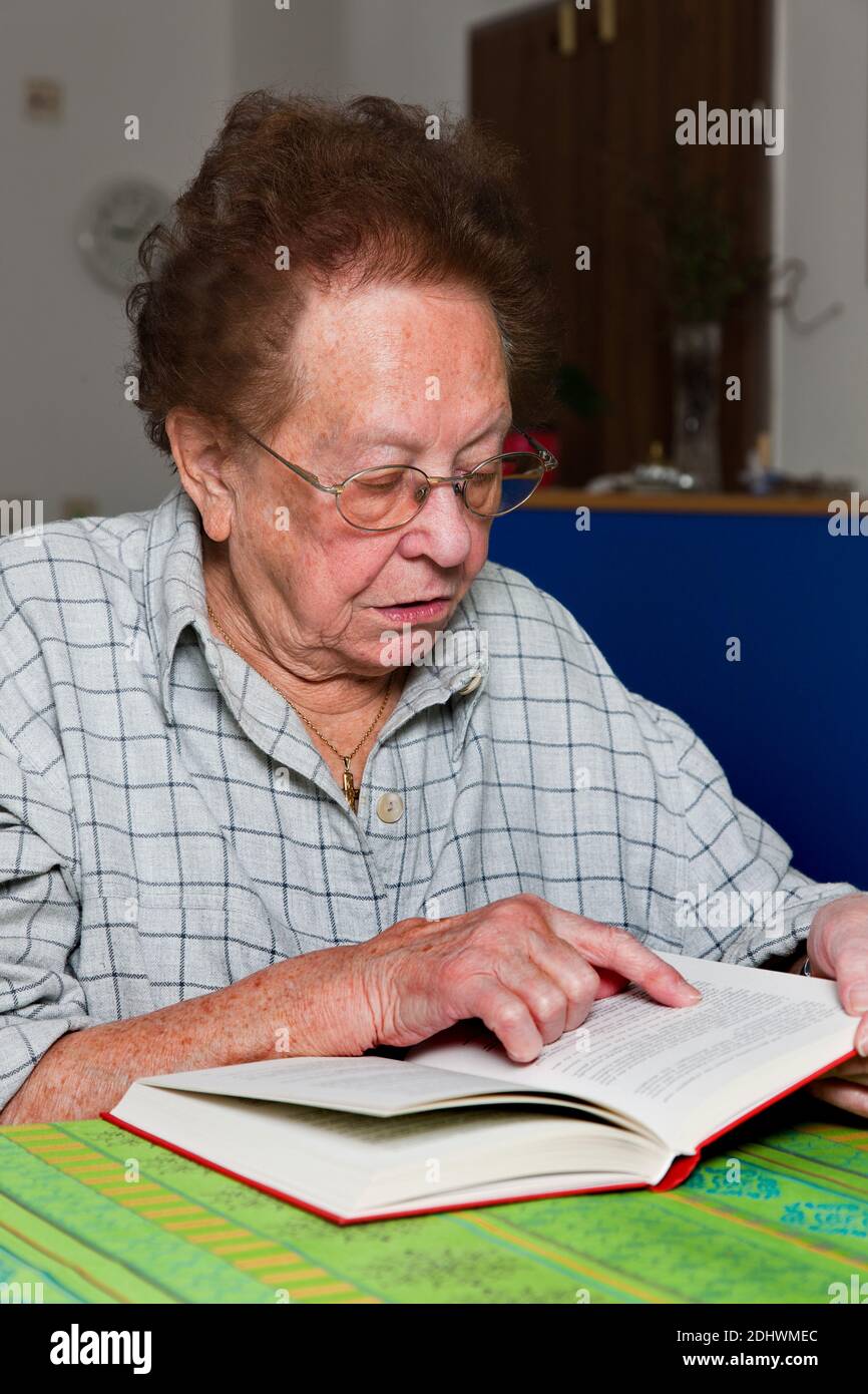 Alte Frau mit Brille liest ein Buch Stock Photo