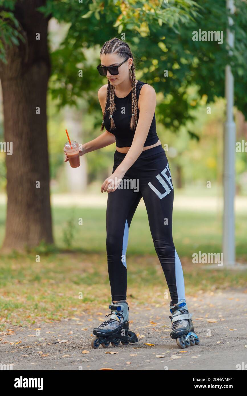 Young girl with hair braids learning to ride on roller skates and how