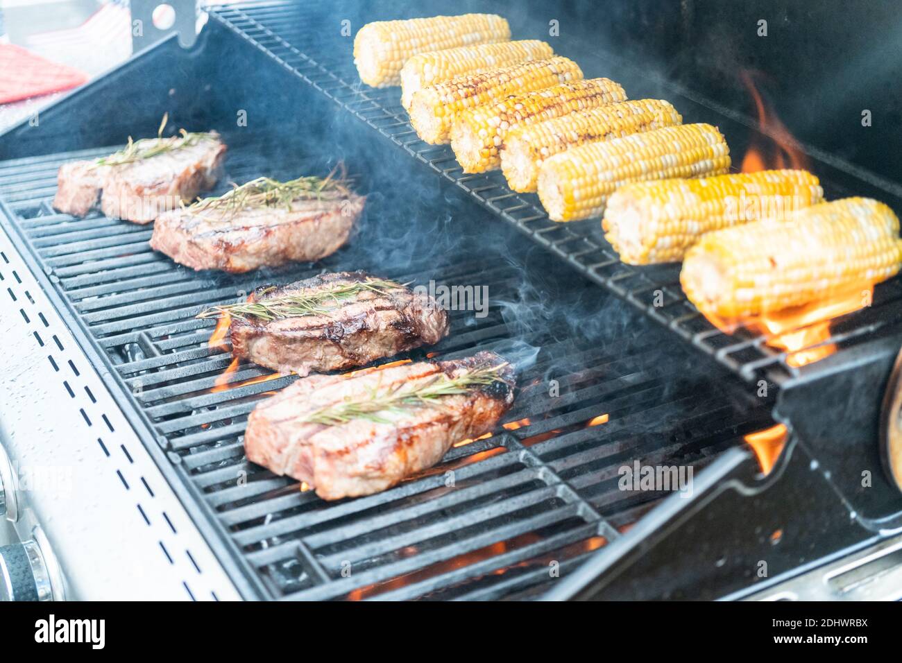 Grilling New York steak with a slice of butter and rosemary on an