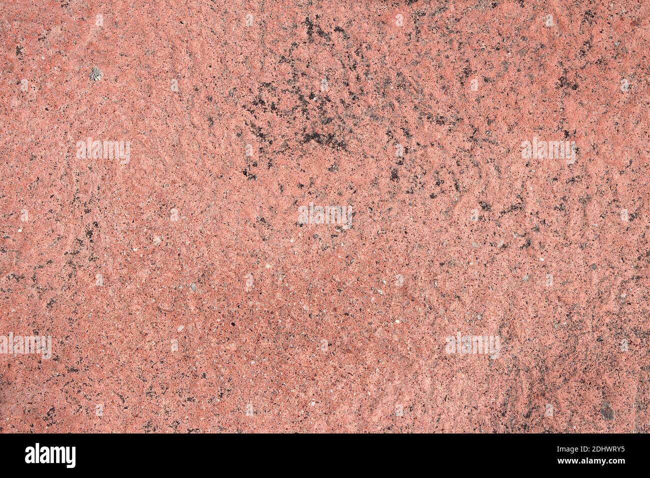 Rough reddish stone and sand texture background with black spots of ash ...