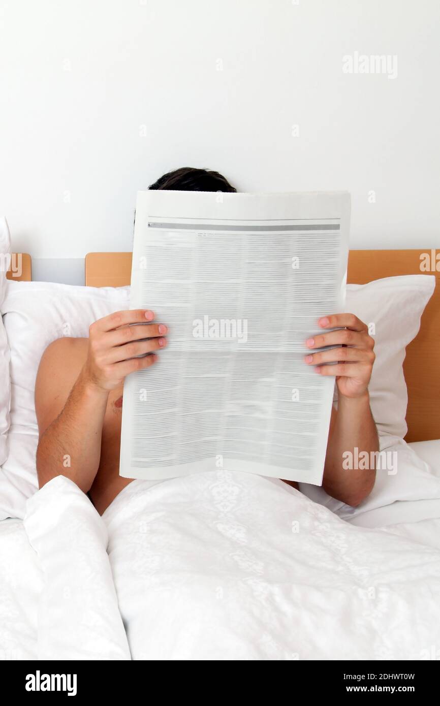 Mann  liest die Zeitung im Bett, Information und Nachrichten, Stock Photo