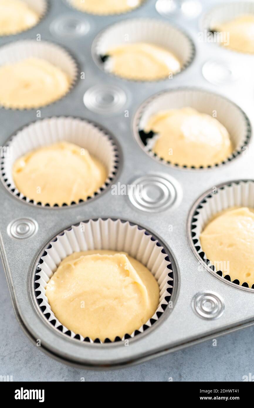 Vanilla cupcake batter in foil cupcake liners to bake Mardi Gras