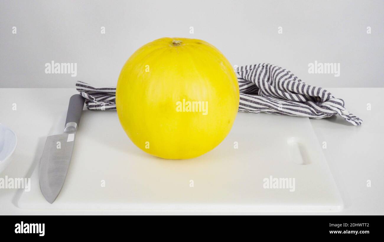 Step by step. Whole golden dewlicious melon on a white background Stock