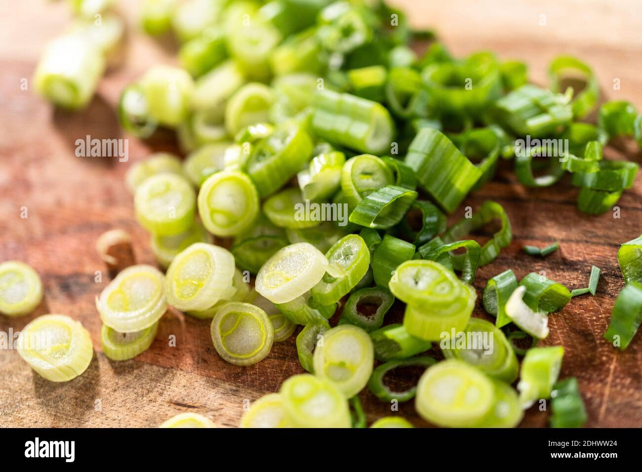 Cutting organic green onions on a wood cutting board Stock Photo - Alamy