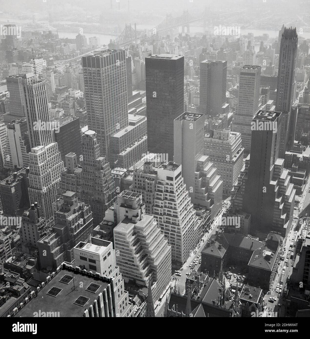 1960s, historical aerial view from this era over Manhattan, New York city, showing the density of the area, the tall buildings, the Tower blocks and skyscrapers and the Brooklyn Bridge in the far distance. Stock Photo