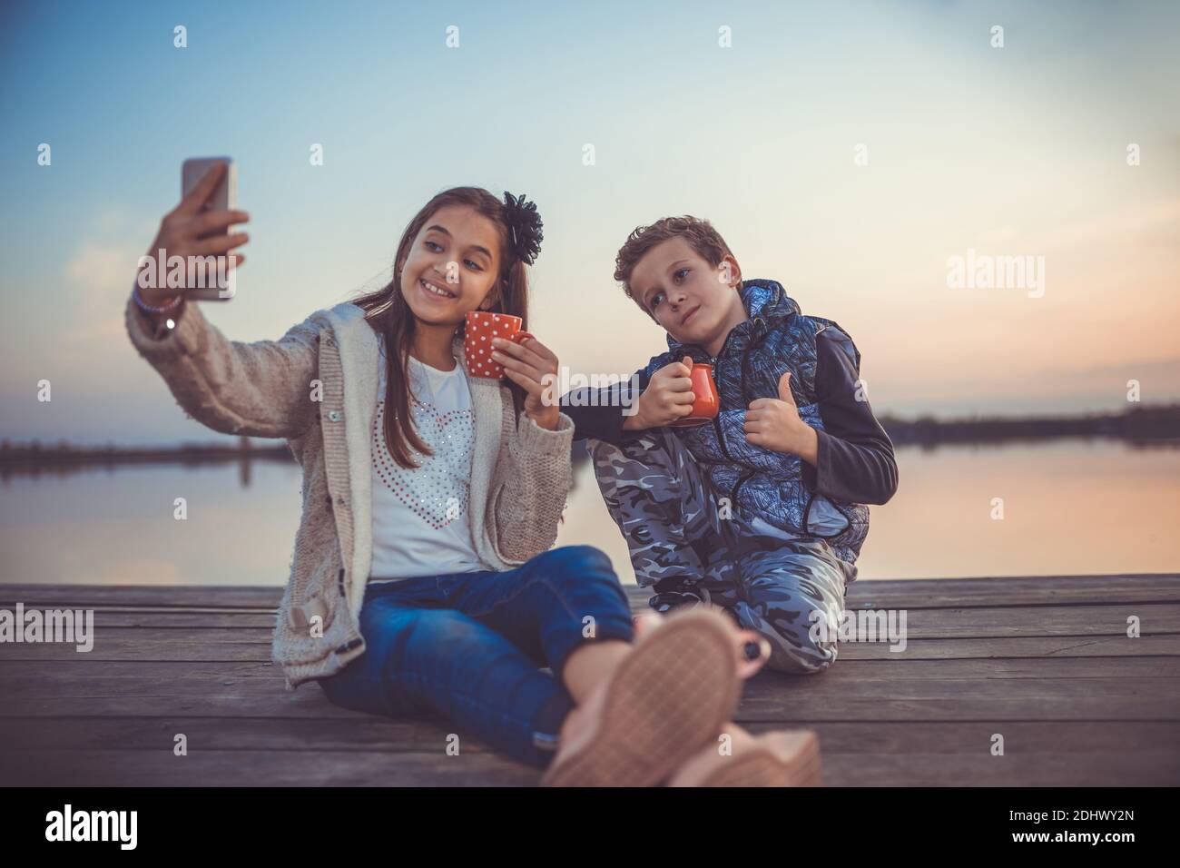 Two Young Cute Little Friends Boy And Girl Having Fun And Drinking Tea While Sitting And Taking Photo By The Lake In The Evening Girl Taking Selfie Stock Photo Alamy