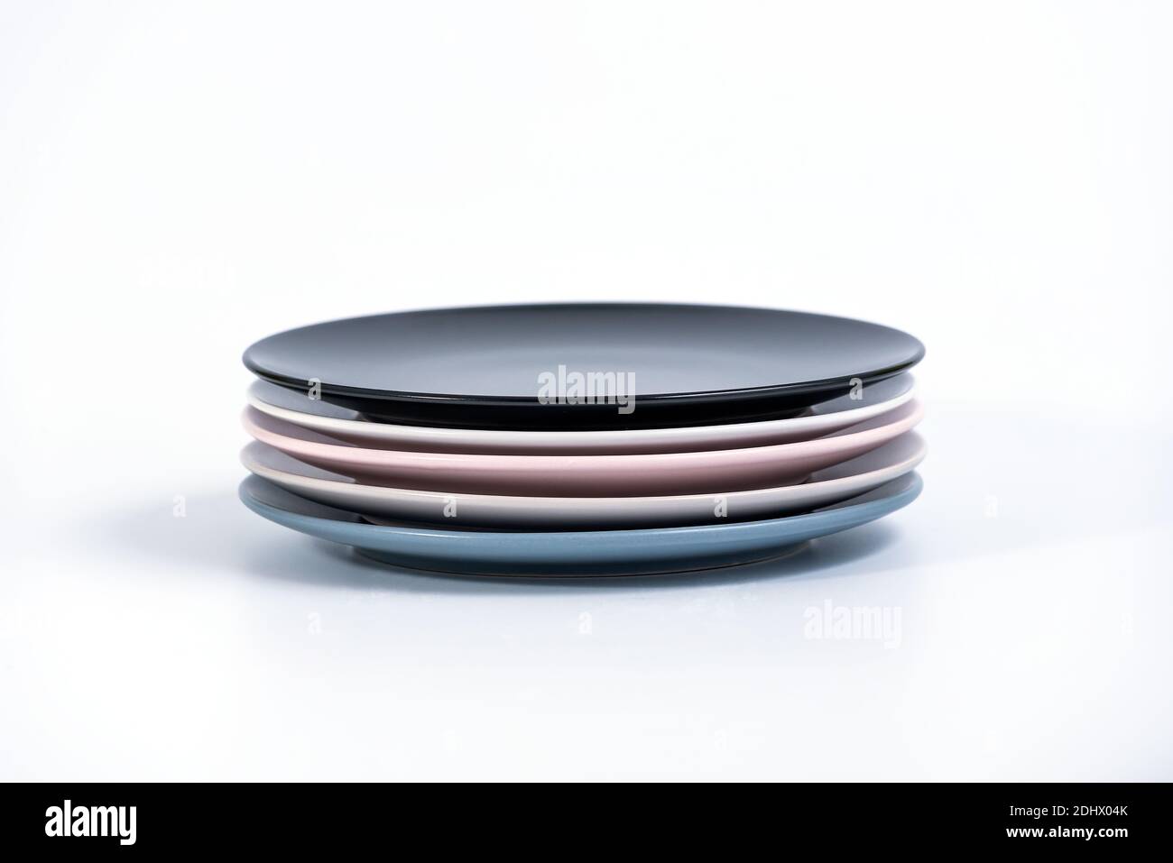 Stack of five colorful empty plates isolated on white background, side ...