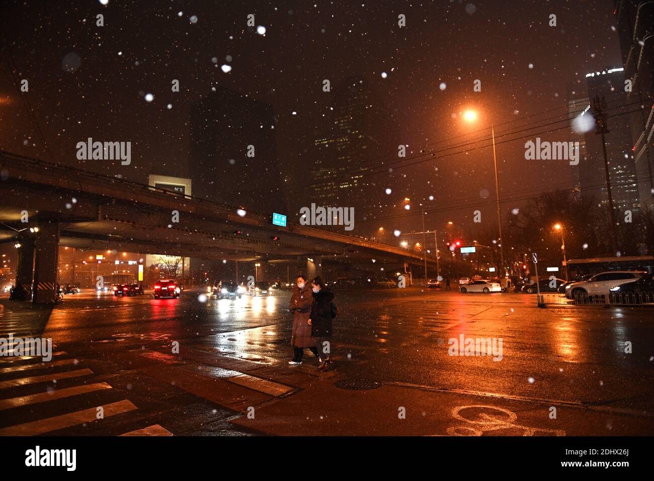 Beijing, China. 12th Dec, 2020. People walk in snow near Jingguang Bridge in Beijing, capital of China, Dec. 12, 2020. Beijing witnessed a snowfall on Saturday evening. Credit: Ju Huanzong/Xinhua/Alamy Live News Stock Photo