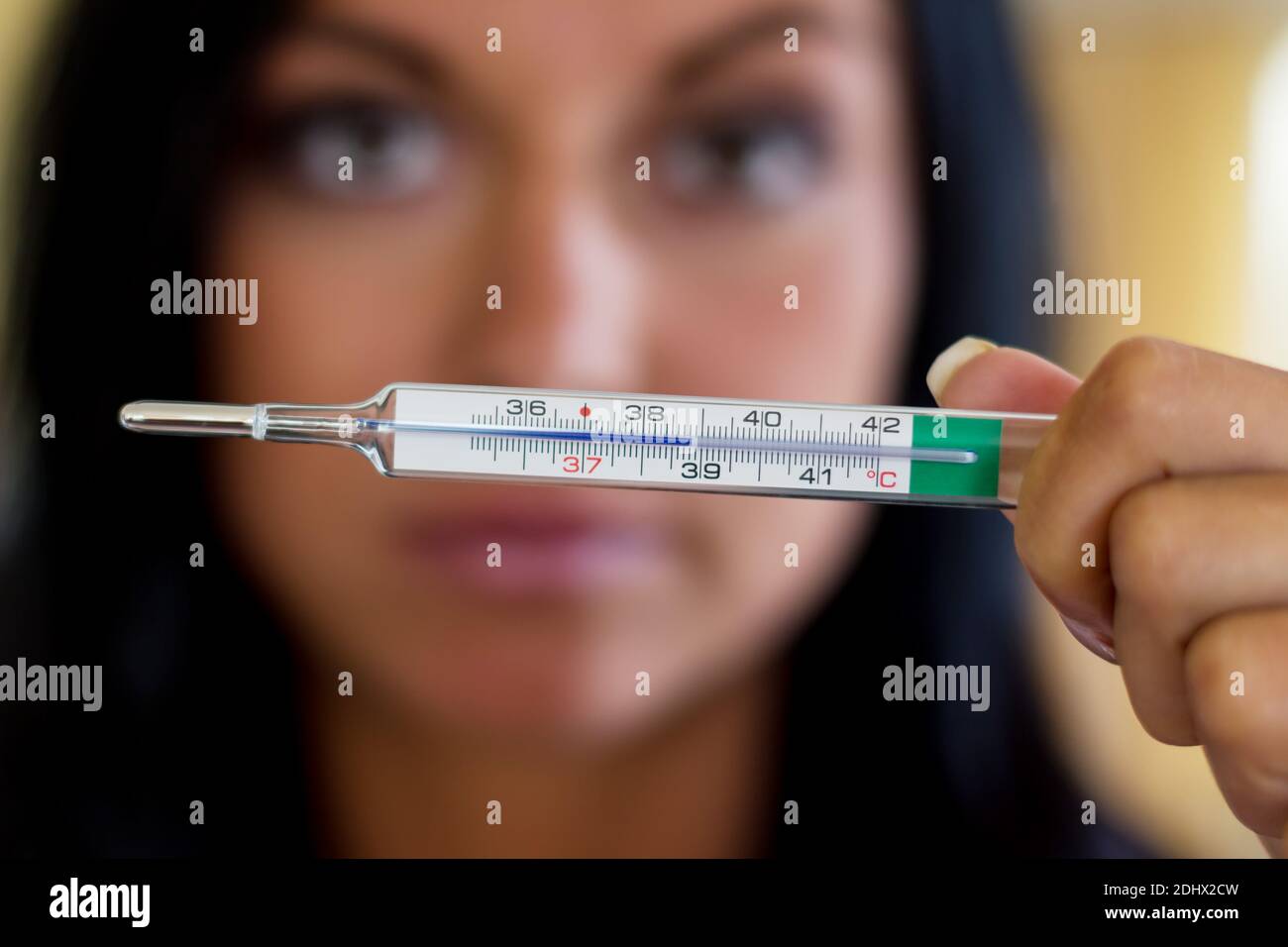 Eine Frau haelt eine Fieberthermometer in der Hand, 38,8 Grad,  Symbolfoto für krank und Fieber, MR: YES Stock Photo