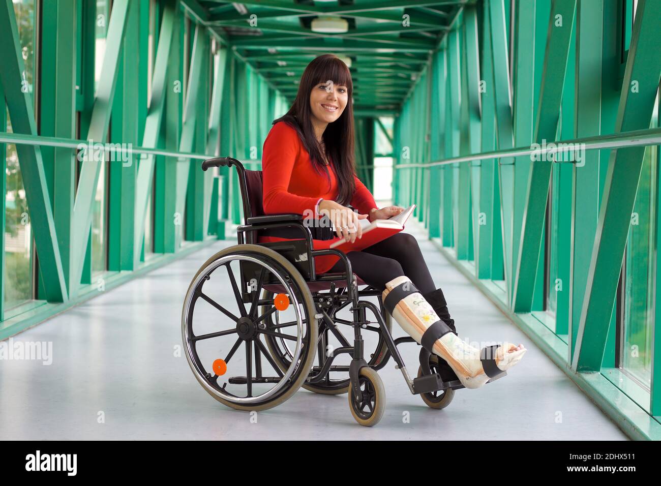 Junge Frau mit Gipsbein sitzt im Rollstuhl, MR: Yes Stock Photo