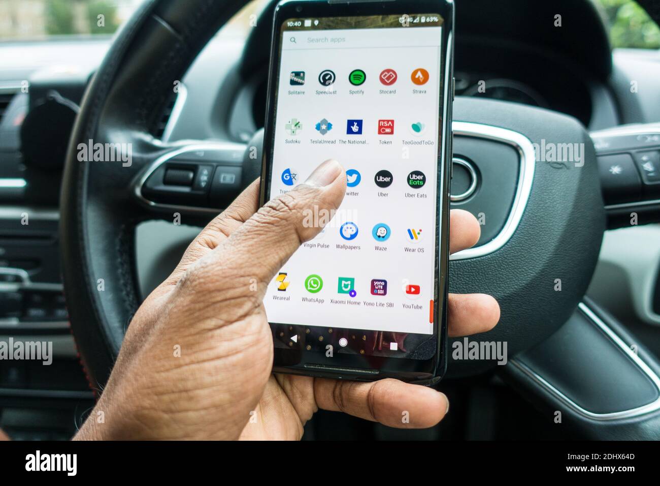 Operating mobile phone behind the wheels of car Stock Photo